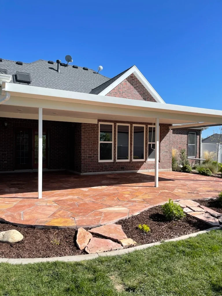Terracotta brick patio with stone edging and landscape beds beside brick home