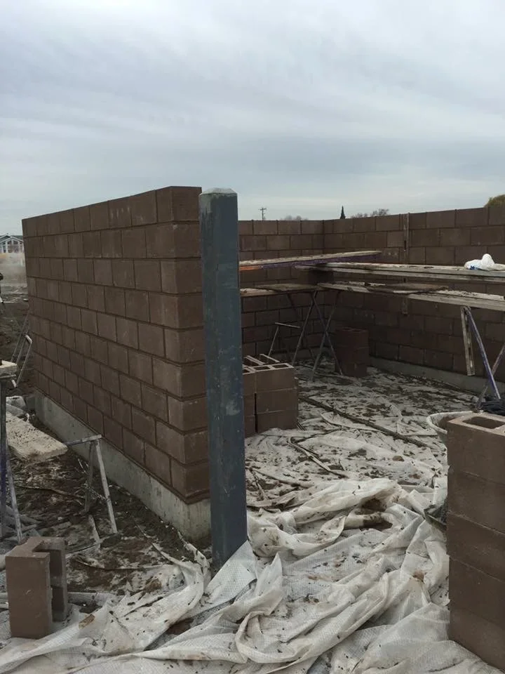 Brown brick masonry walls with steel post and concrete foundation during construction