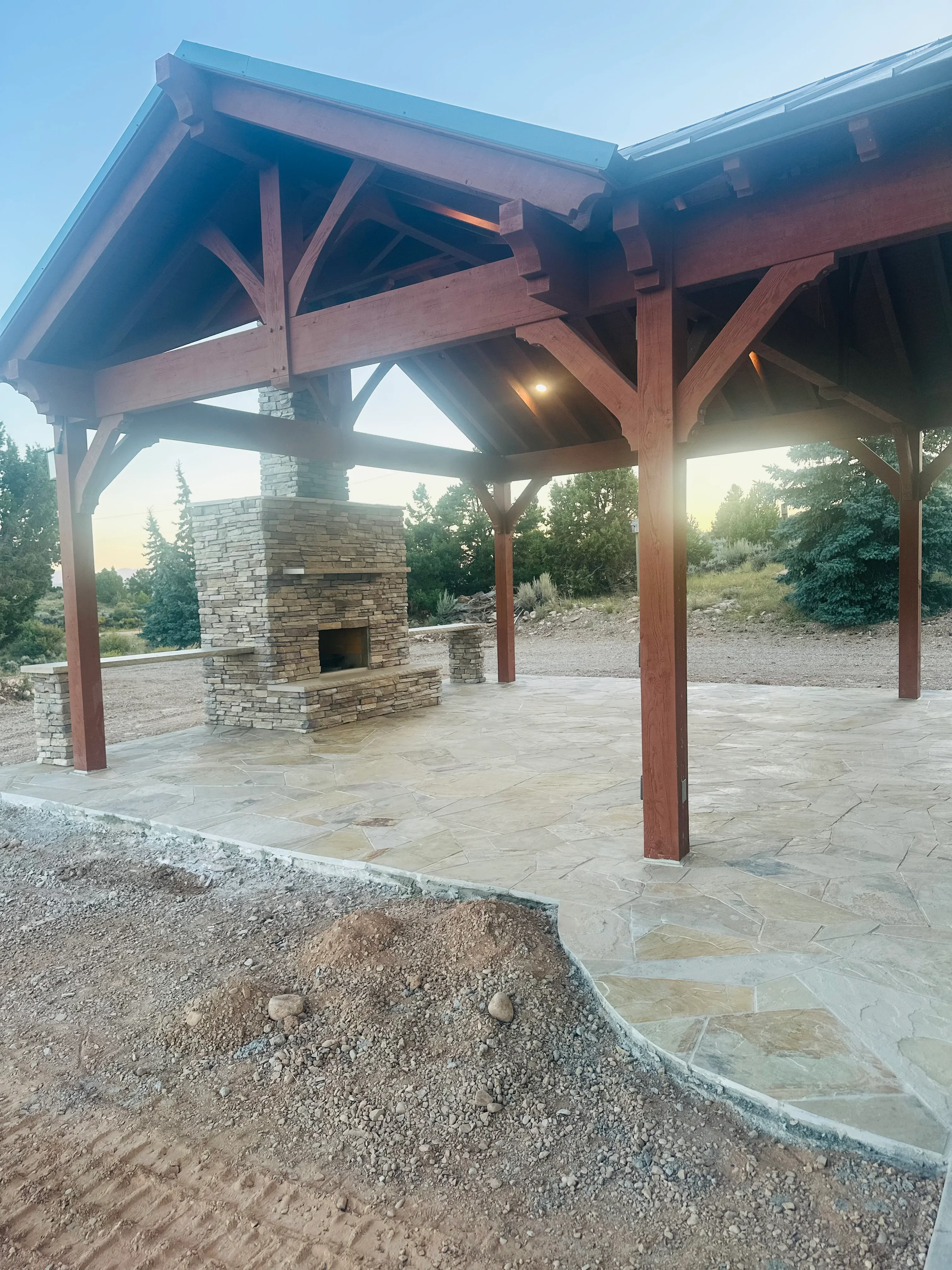 Stone fireplace and chimney with flagstone patio under timber pavilion