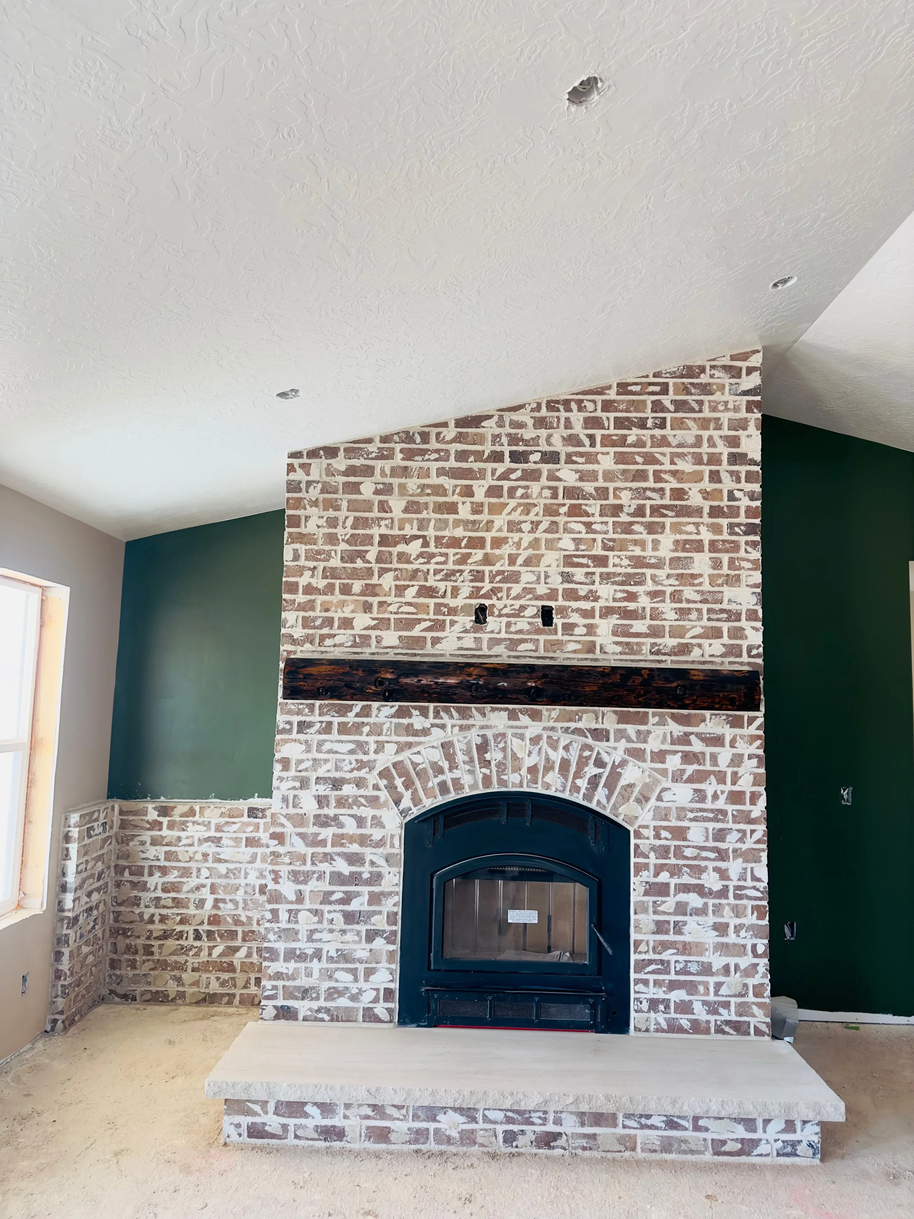 Tan and red brick fireplace with arched opening and black metal insert