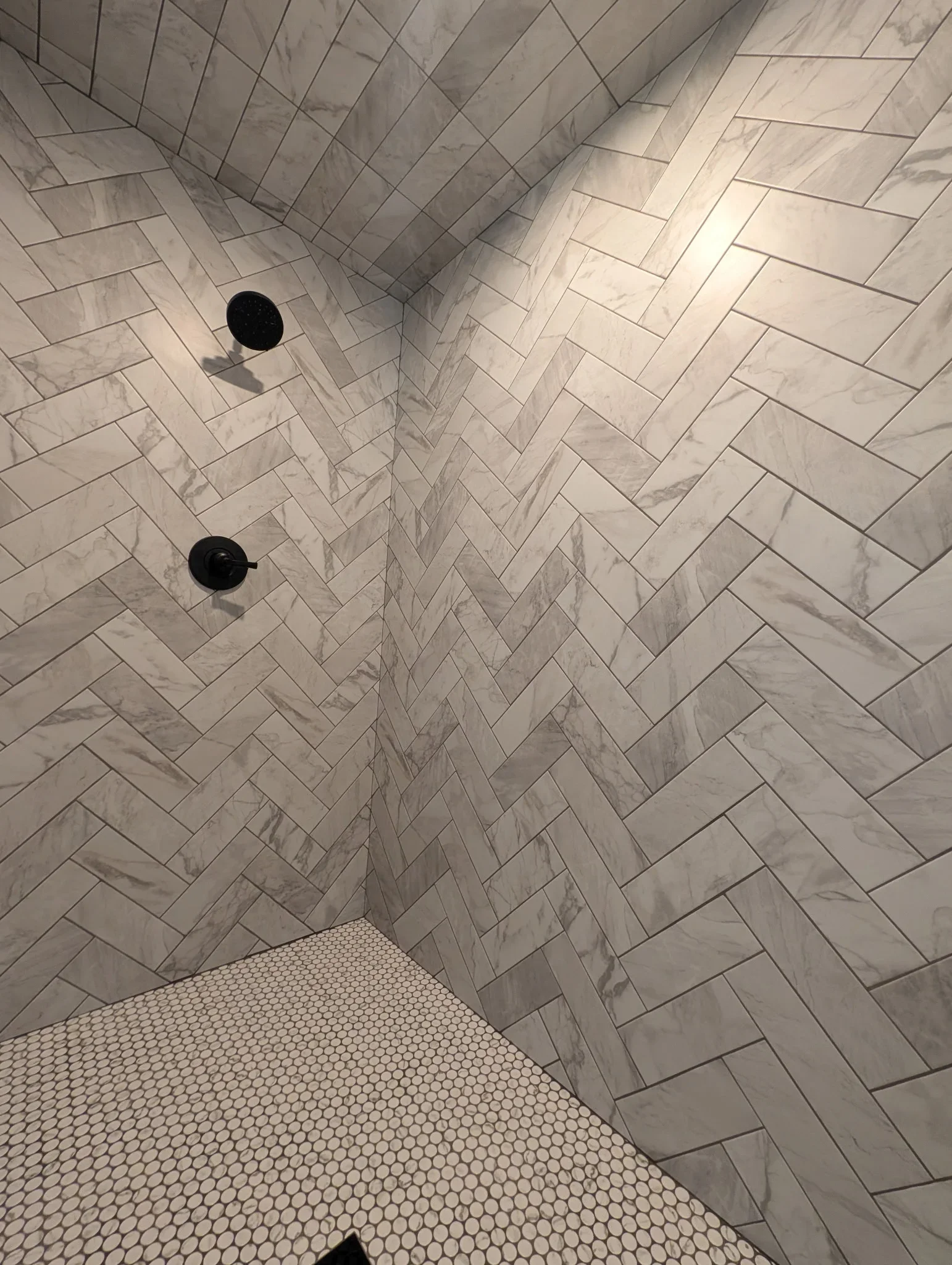 Marble herringbone subway tile shower walls and ceiling with penny round tile floor