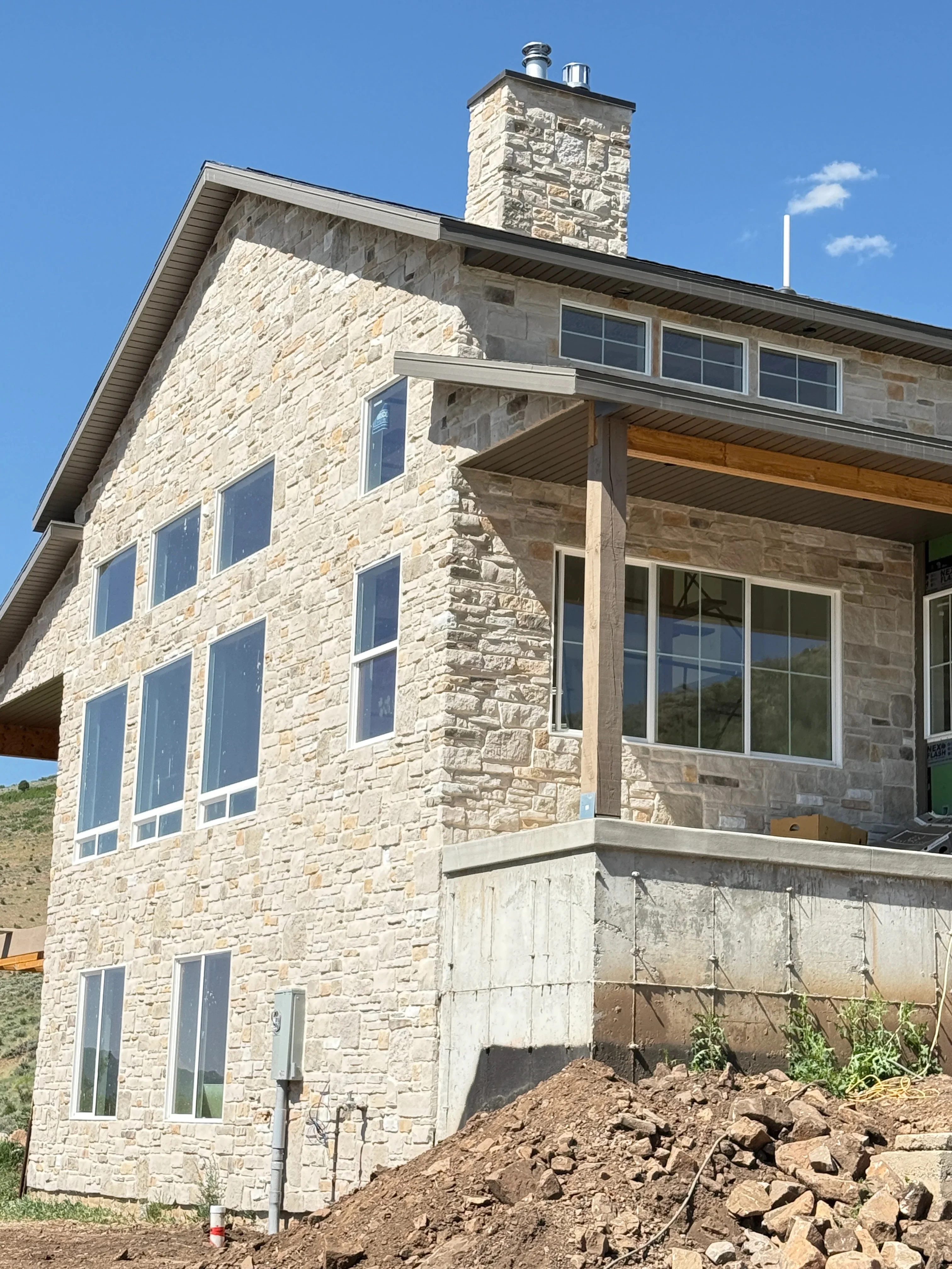 Cut stone veneer masonry on multi-story residential home with chimney and window openings